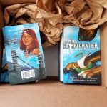 A box of books with copies of the YA fantasy novel The Trickster